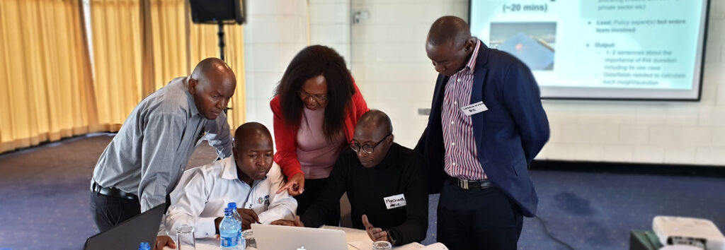A group of people looking at a laptop at a workshop.
